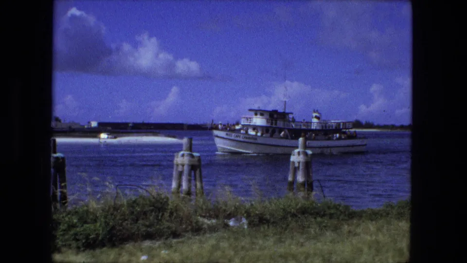 Near the end of the clip, the passenger boat sits farther right against blue water and sky in the supplied 1974 Fort Wayne footage.