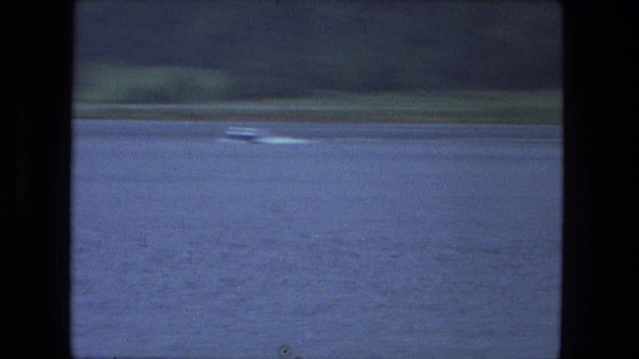 Small motorboat and bright wake on a blue lake in the 1974 Fort Wayne-area home-movie footage.