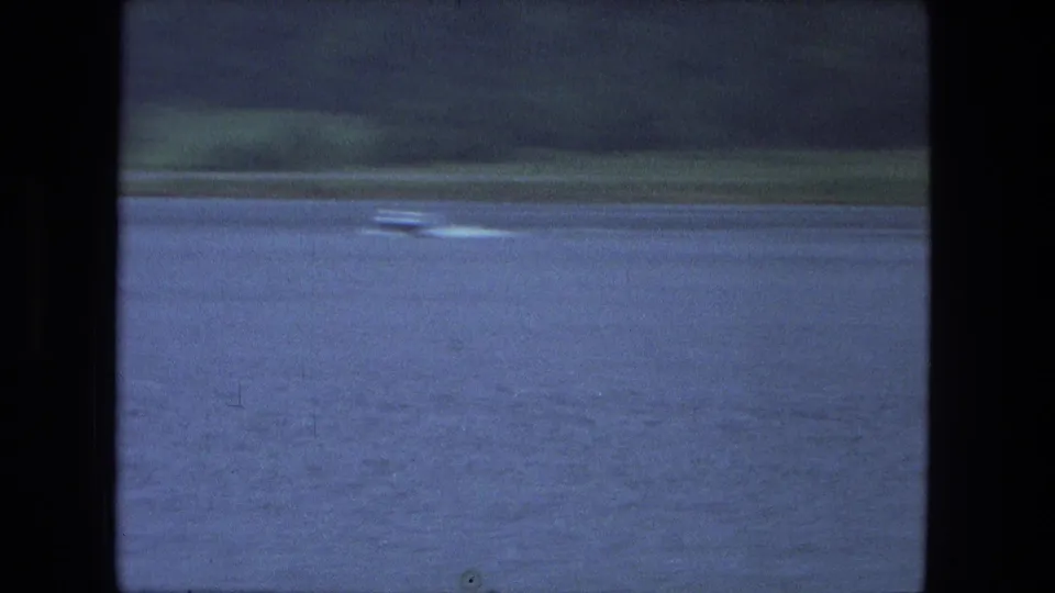 Small motorboat and bright wake on a blue lake in the 1974 Fort Wayne-area home-movie footage.