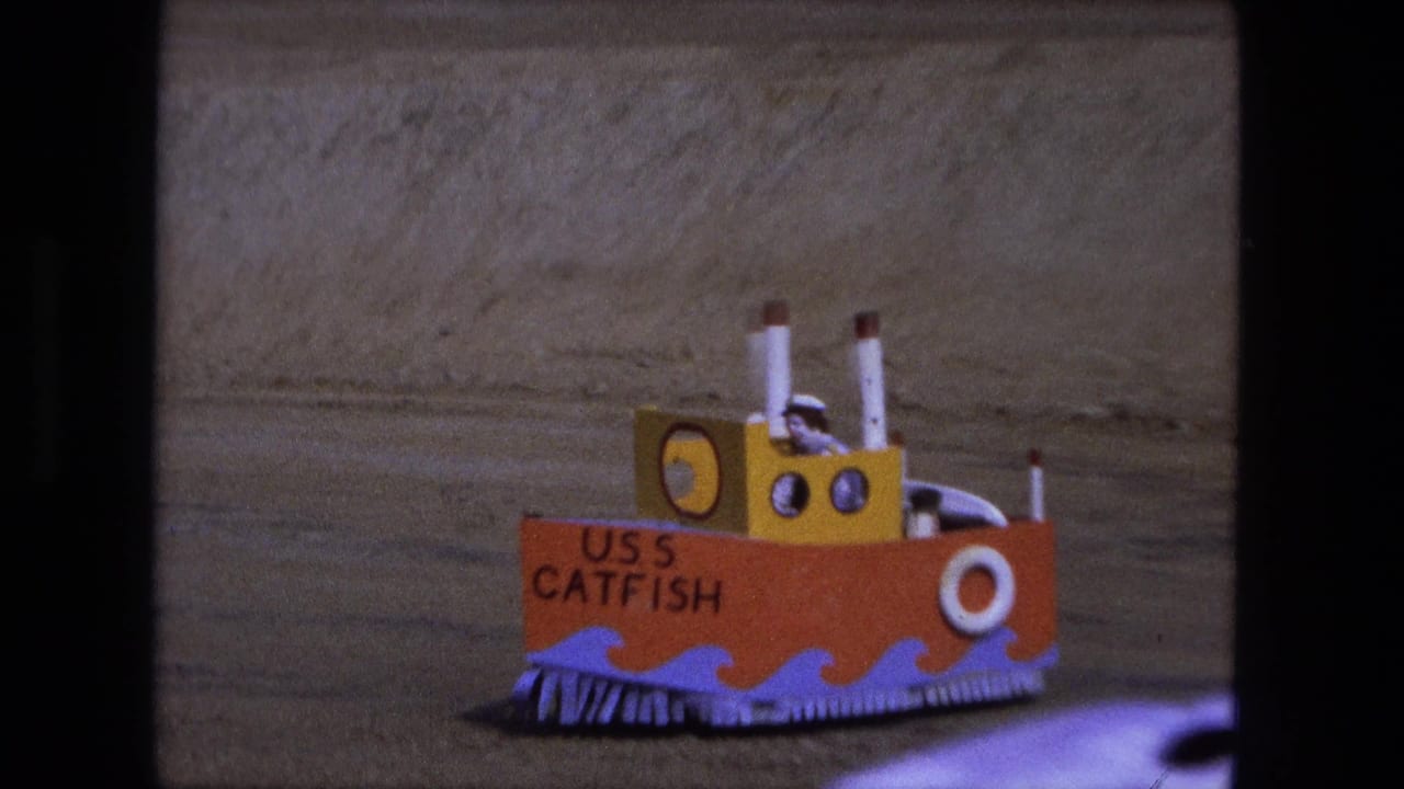 Homemade USS Catfish model boat on sandy ground.