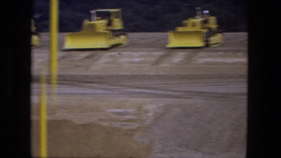 Soft 8mm frame from Fort Wayne in 1974 showing bulldozers moving over a broad graded excavation surface.