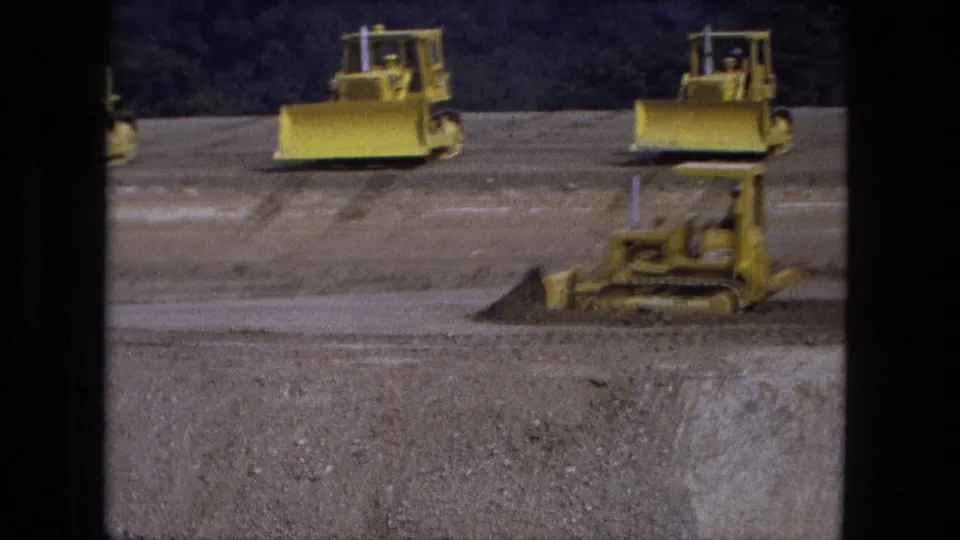 1974 Fort Wayne 8mm frame showing several yellow bulldozers at different distances on an excavation site.