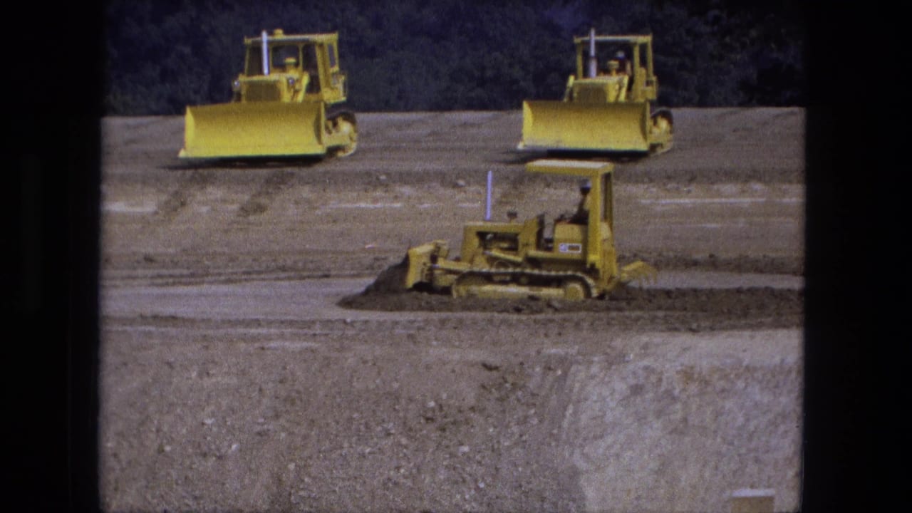 Yellow bulldozers work across a broad dirt construction site.