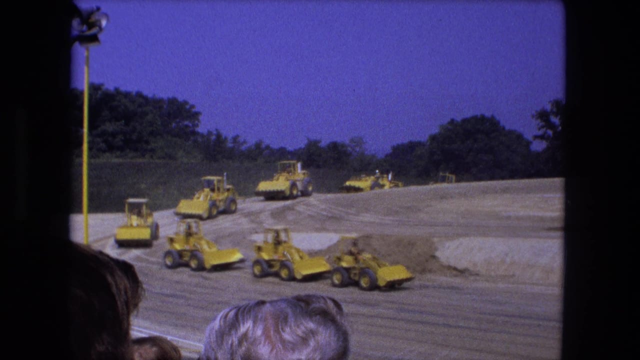 1974 Fort Wayne frame with multiple yellow tractors and bulldozers arranged across a large dirt site under a blue sky.