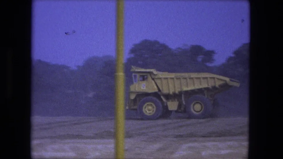 1974 Fort Wayne 8mm frame showing a yellow dump truck on a dirt road, partly interrupted by a vertical film-strip divider.