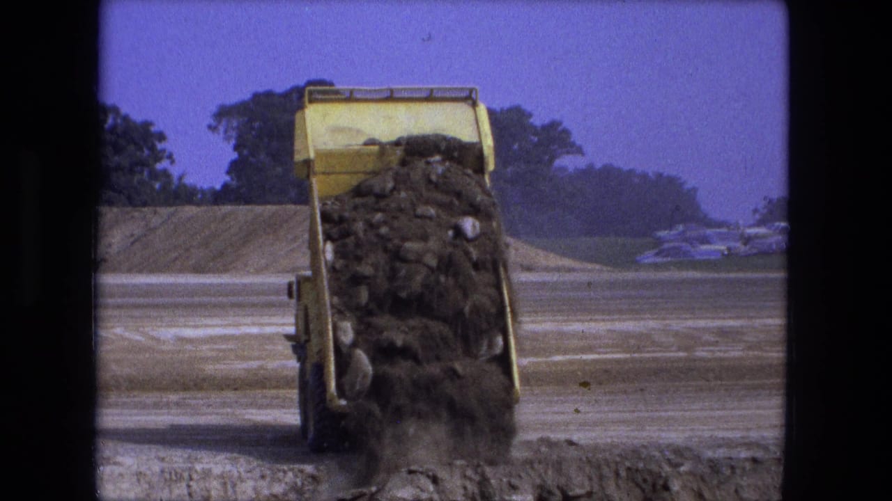 Dump truck bed pours a larger load of dirt onto the road surface.