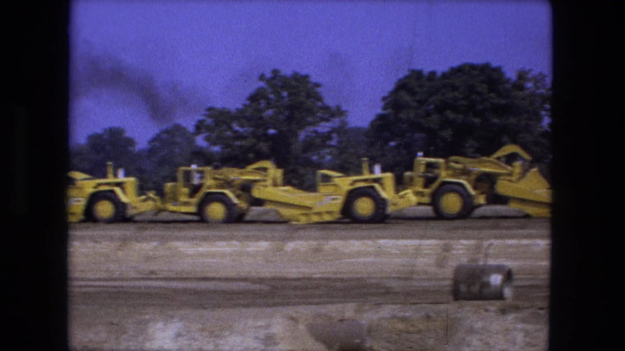 Two yellow earth movers sit side by side on a scraped construction lot.