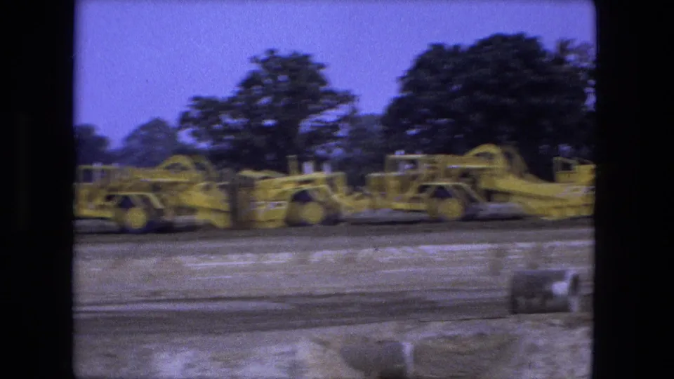 Yellow road graders operate across a Fort Wayne construction site in this 1974 8mm home-movie frame.