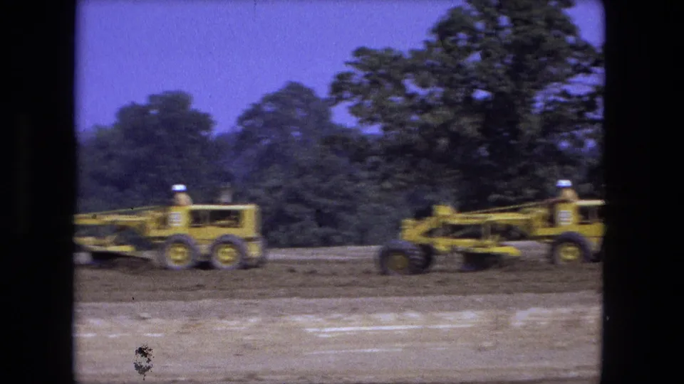 End frame from the 1974 Fort Wayne clip showing yellow graders in motion across an open construction area.