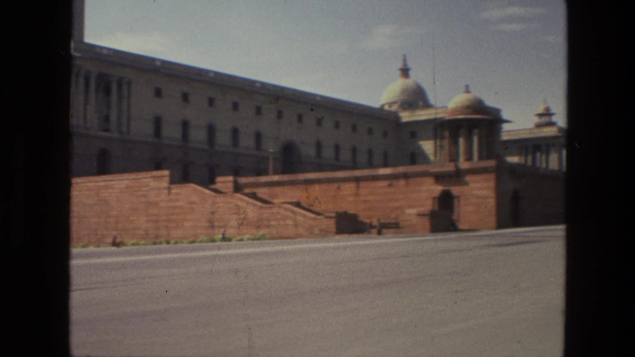 Red sandstone wall and domed building facade seen from across an empty road.