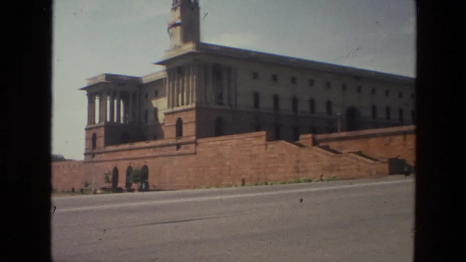 1974 India frame showing a colonnaded corner tower and long government-style facade above red sandstone walls.