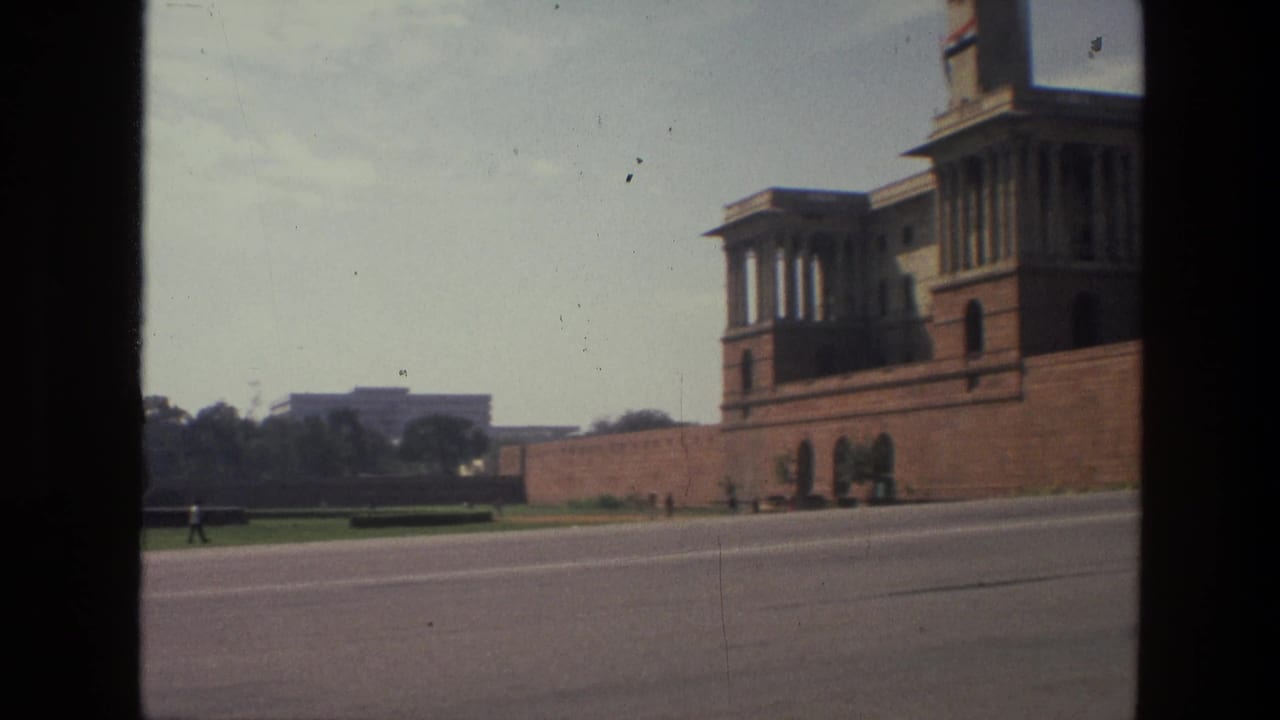 Wide road beside a large formal building with lawns and trees in the distance.
