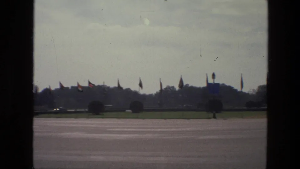 A wide 1974 India civic view shows an open paved area with flags, trees, lawns, and distant architecture.