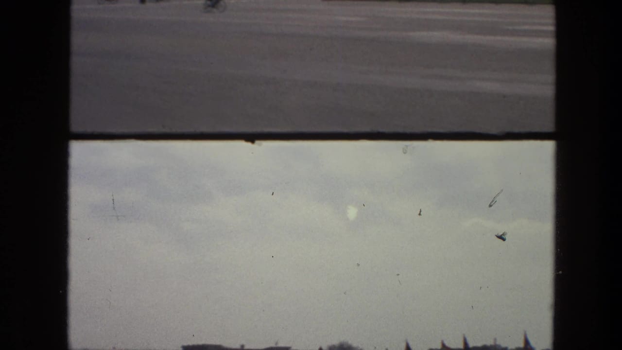 Mostly overcast sky and horizon line seen through a dark window frame above a roadway.