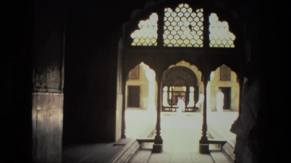 The final 8mm frame shows a dark interior opening onto a bright arched passage with ornate latticework.