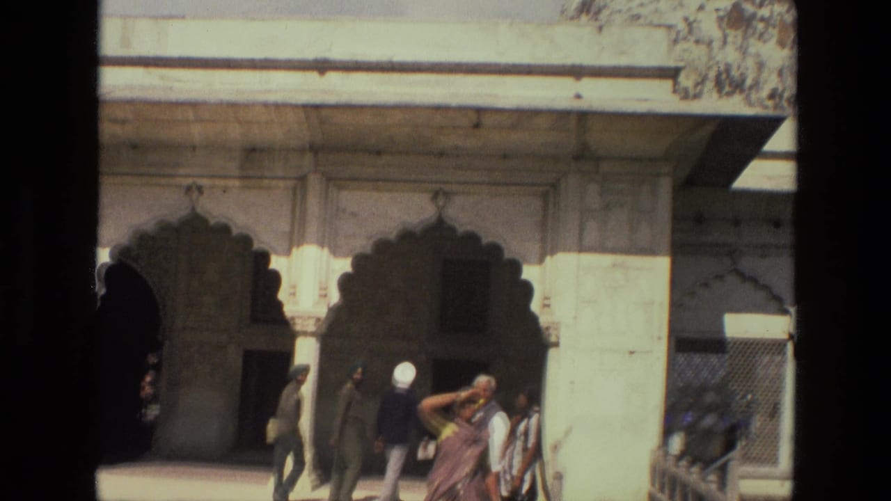 1974 India frame with ornate arched palace openings, a bright stone facade, and visitors moving through the courtyard.