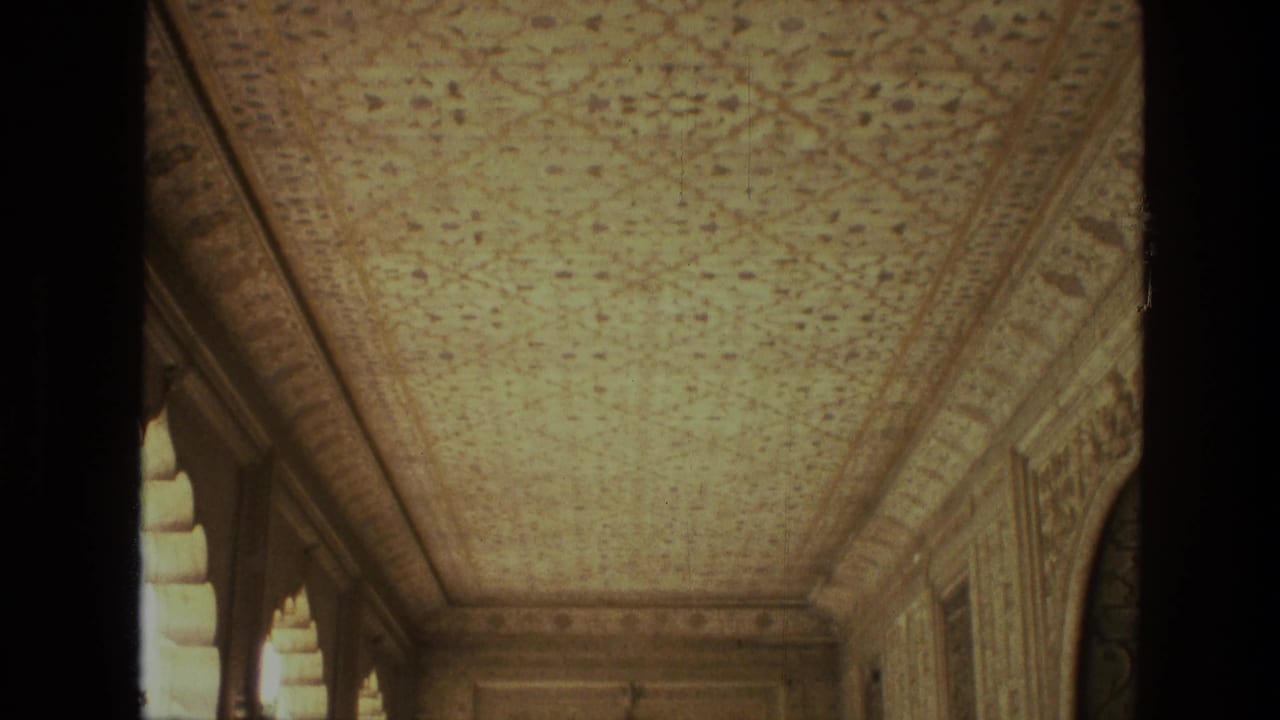 Ornate ceiling and arched corridor seen from a visitor perspective.