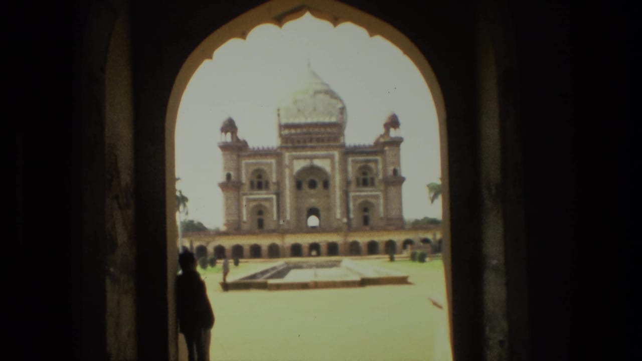 Symmetrical domed monument viewed through an arch with a silhouetted person near the left edge.