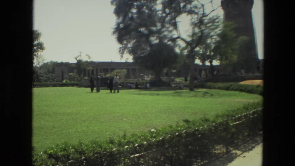 Visitors gather on the green grounds of the Qutub Minar complex in 1974 India home-movie footage.