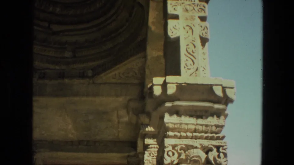 Close home-movie view of carved stone details at the Qutub Minar complex, with sky visible at the edge.