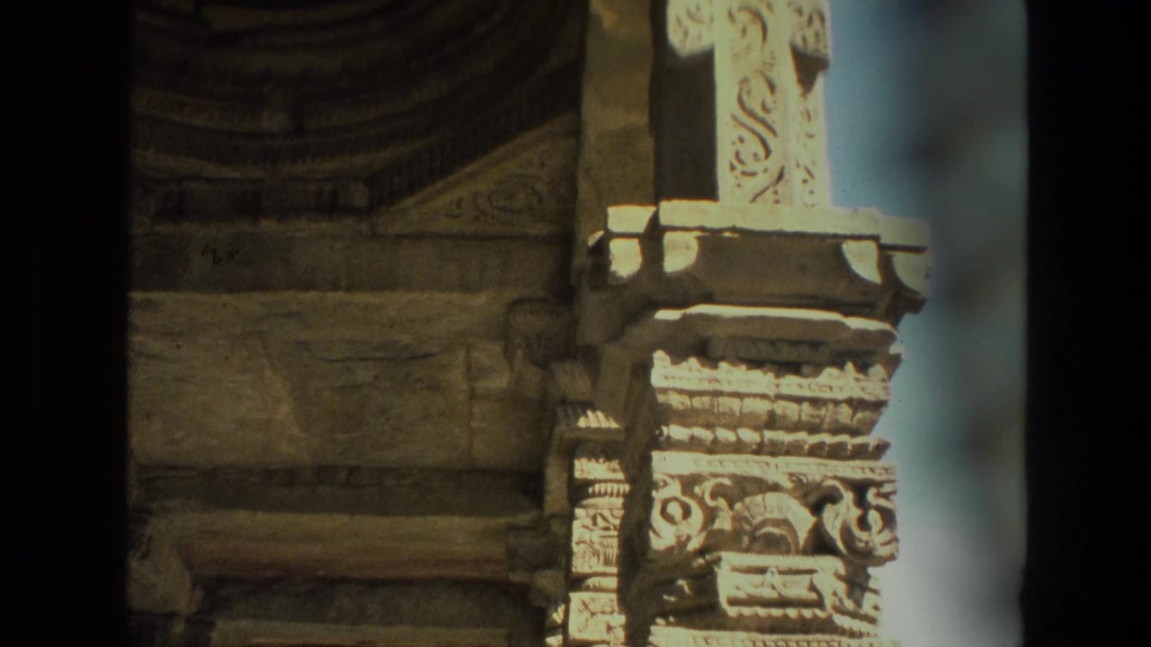 1974 8mm India frame showing carved temple pillars, weathered stonework, and deep shadows in an ancient ruin setting.