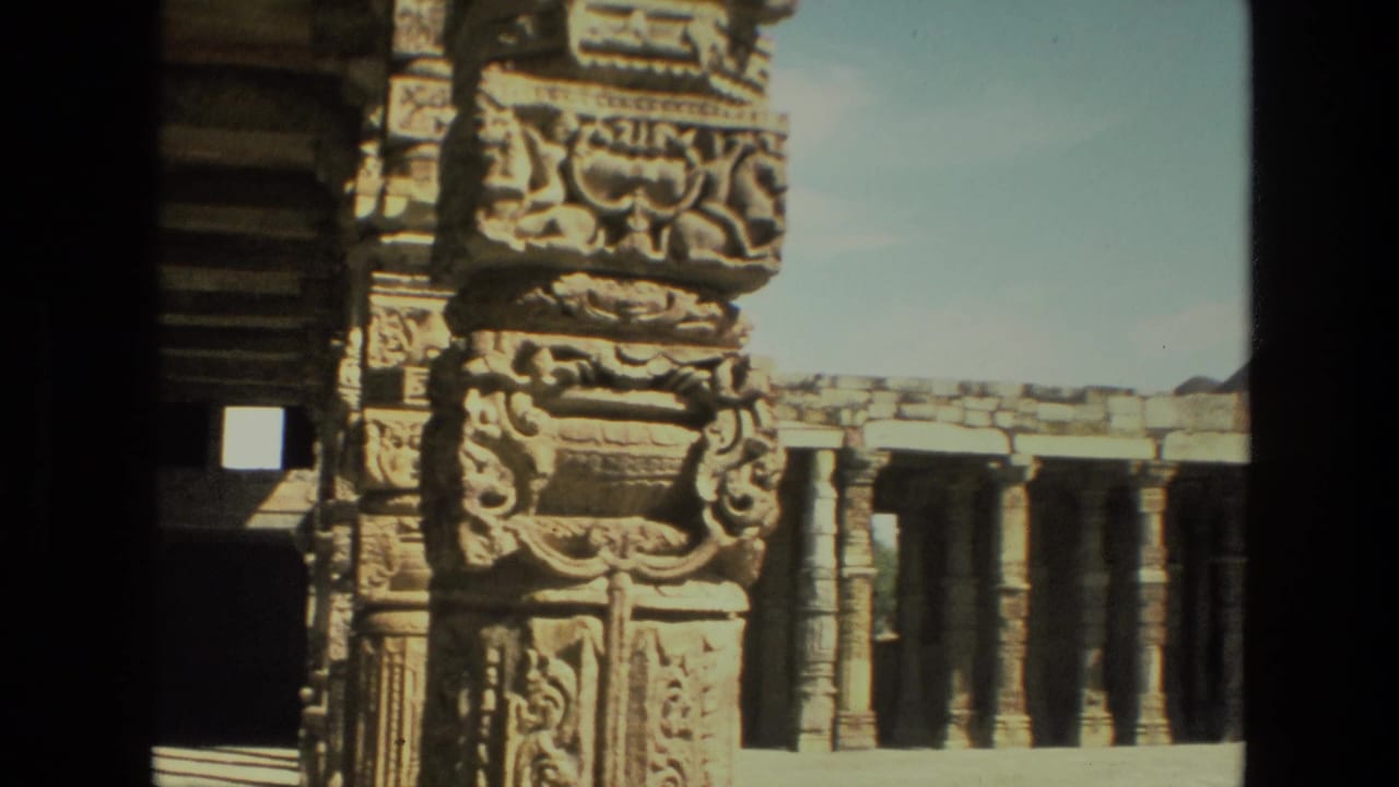Carved stone pillars frame a sunlit colonnade and courtyard.