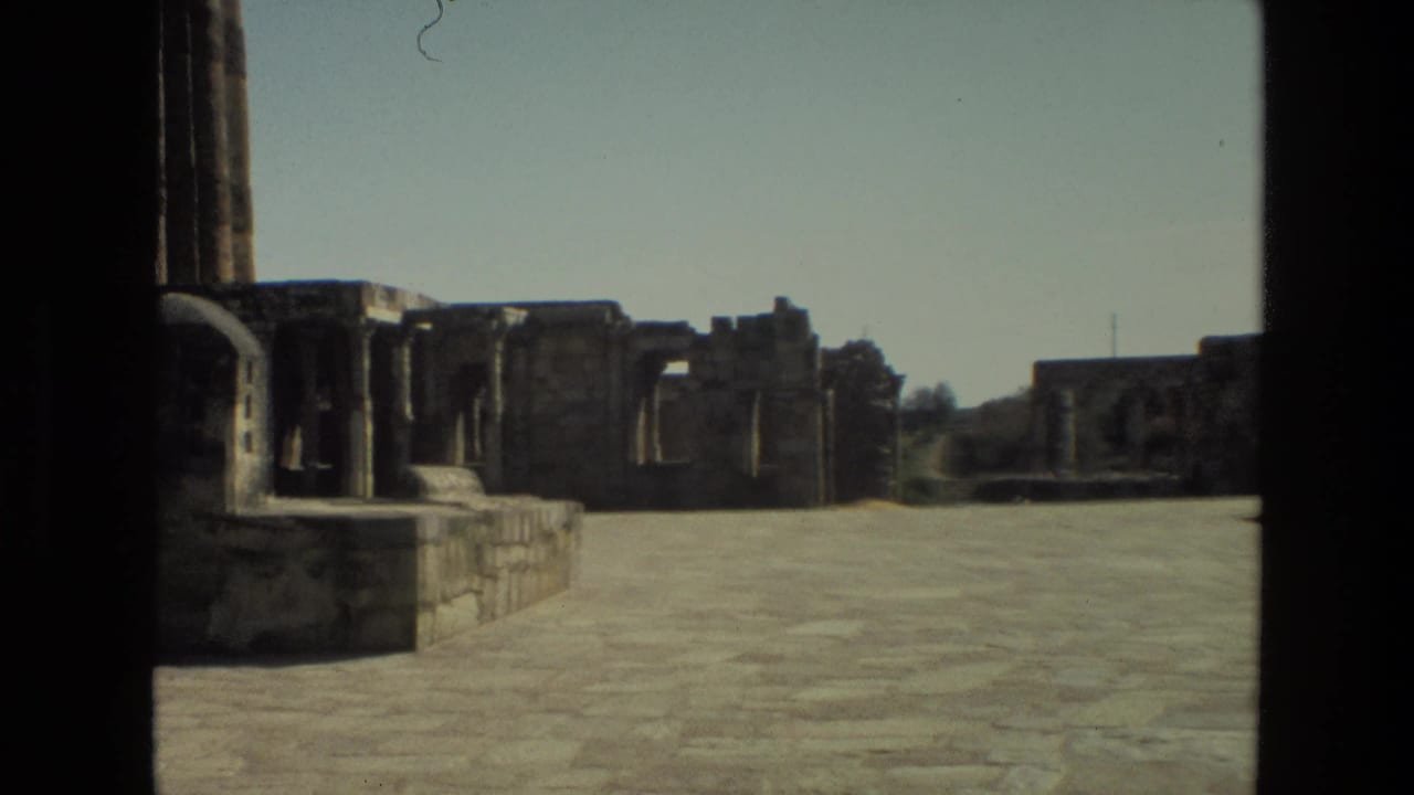 1974 India 8mm view of a stone-paved courtyard with ruined walls and dark vertical framing in the foreground.