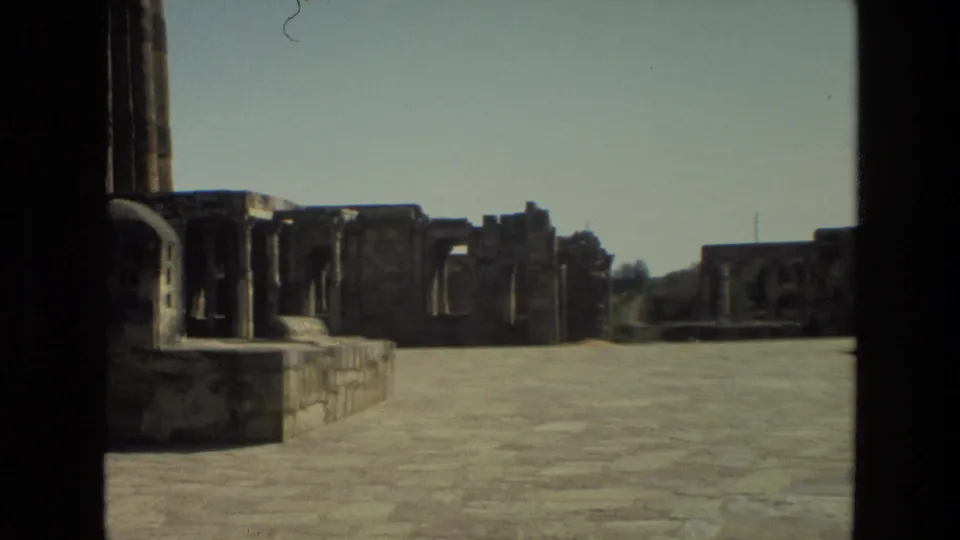 1974 India 8mm view of a stone-paved courtyard with ruined walls and dark vertical framing in the foreground.