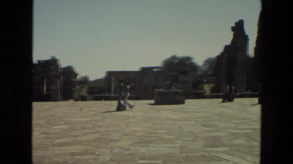 1974 India 8mm view of visitors moving through a paved courtyard with standing fragments of ancient stone ruins.