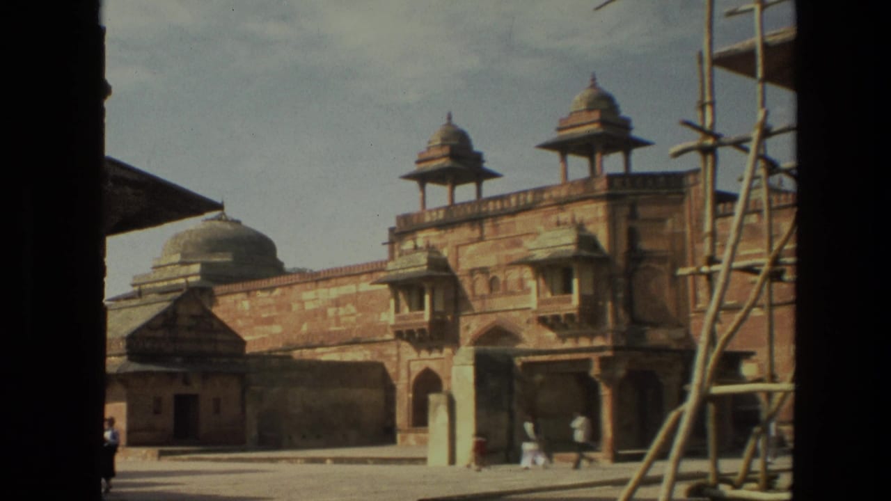 Courtyard view with sandstone walls, domed pavilions, scaffolding, and small visitors.