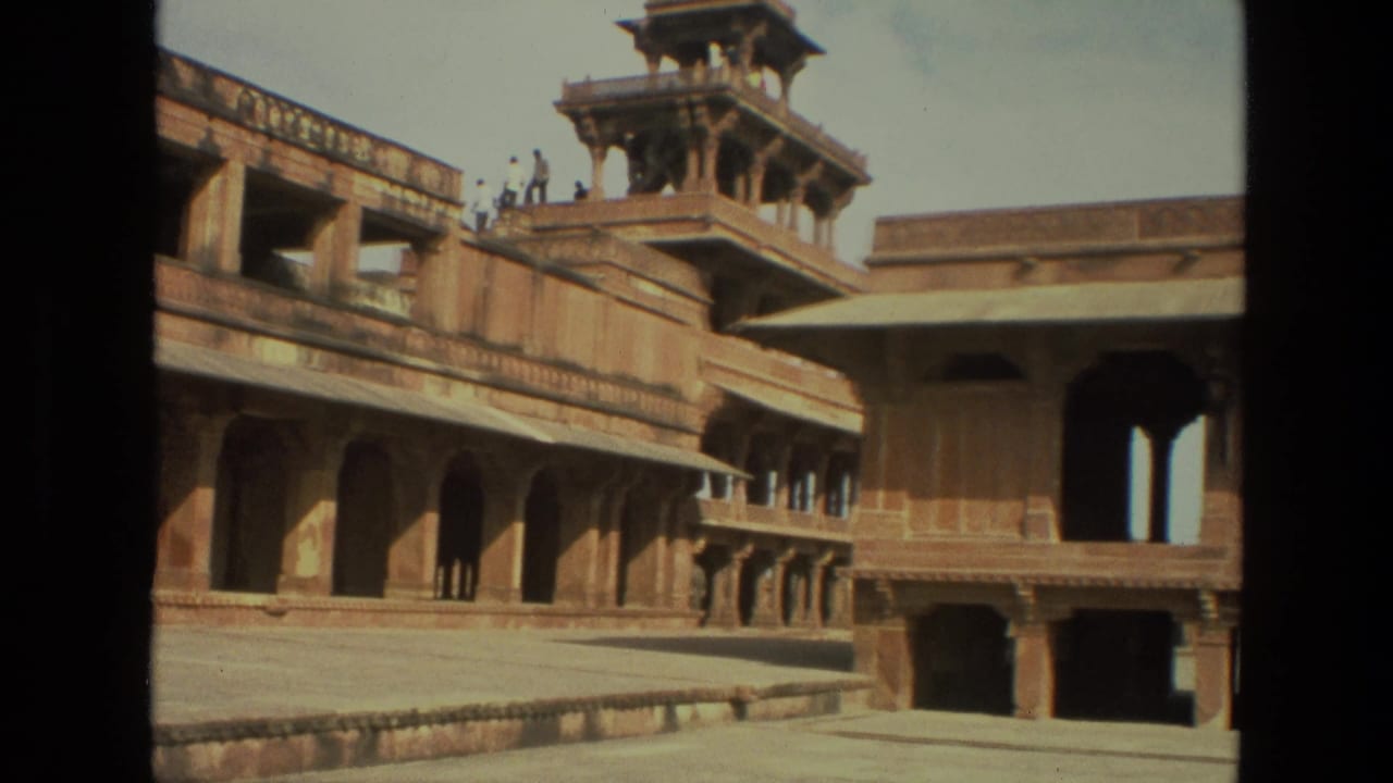 1974 8mm view in India showing a sandstone palace courtyard, arched walkways, and a raised pavilion tower under bright daylight.