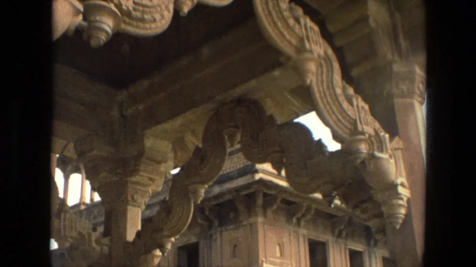 1974 India 8mm frame looking through carved stone colonnades toward another detailed structure.