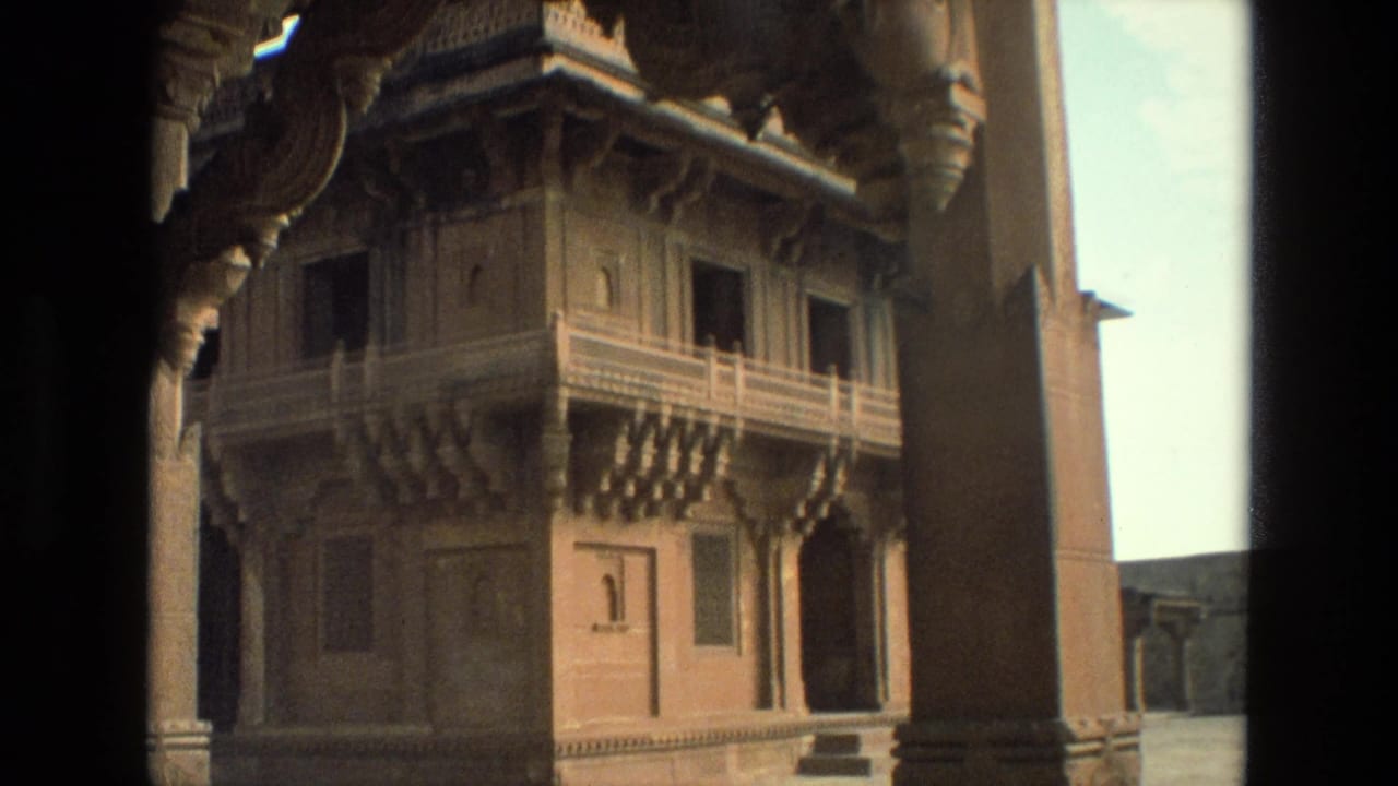 1974 India 8mm frame showing an ornate palace wall with carved balcony details and dark vertical foreground edges.