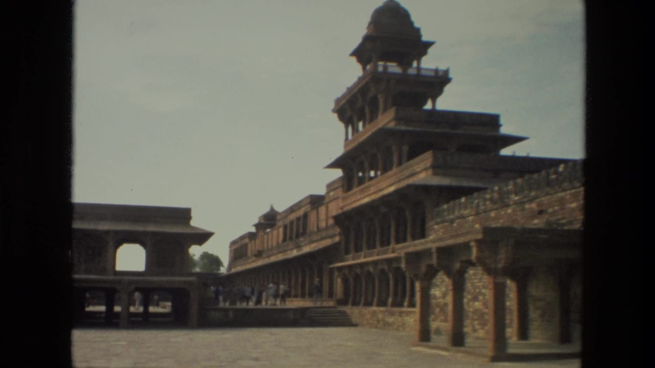 1974 India travel frame showing a broad historic courtyard bordered by arched colonnades and a raised pavilion-like structure.