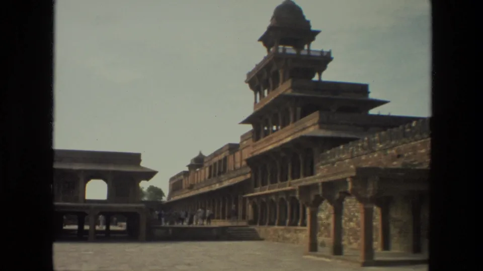 1974 India travel frame showing a broad historic courtyard bordered by arched colonnades and a raised pavilion-like structure.