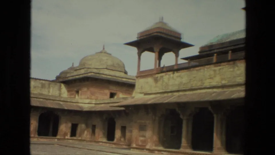 1974 India 8mm frame showing a closer courtyard view with a domed pavilion, open-sided rooftop structure, arches, and weathered stonework.