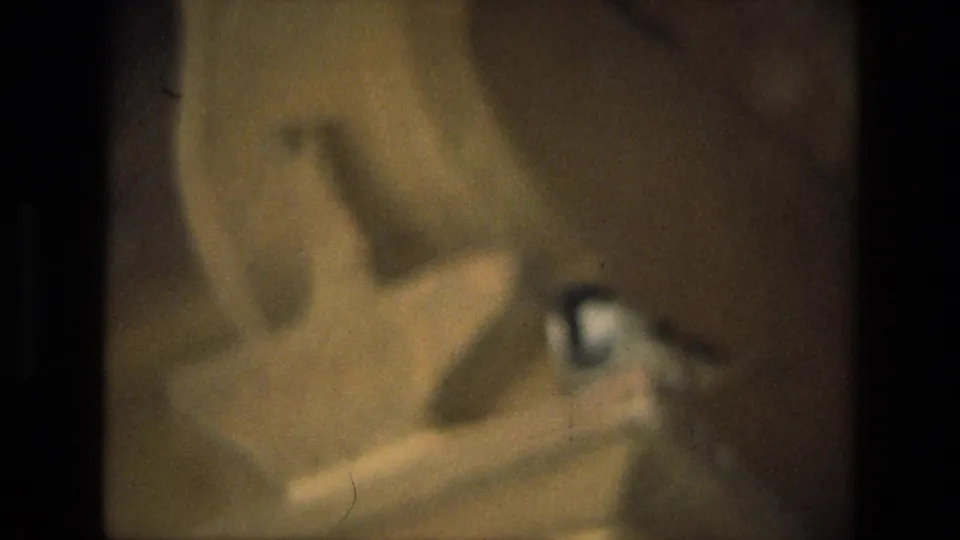 The final 1974 8mm frame is heavily blurred and underexposed, showing indistinct warm-toned shapes beside a dark film-frame edge.