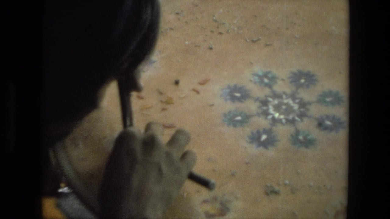 Woman seen from above working on a floral design on a round wooden tabletop.