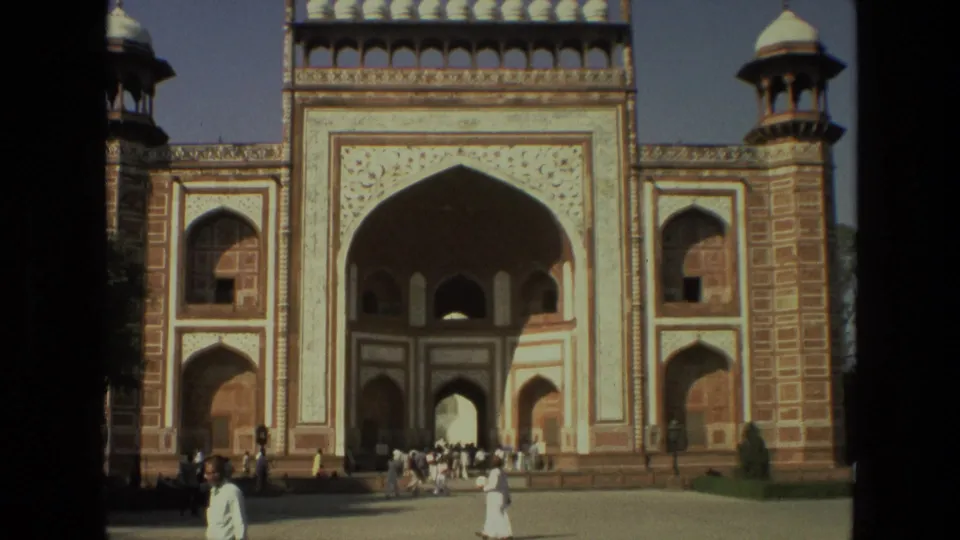 The final frame holds on the ornate Indian gateway and dispersed tourists, with visible 8mm frame edges and warm faded color.