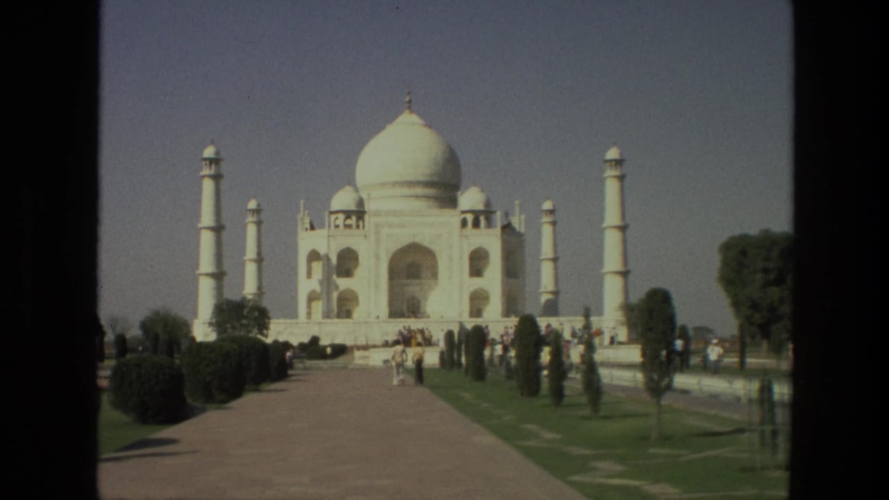 Taj Mahal seen from the garden path with tourists walking in the foreground.