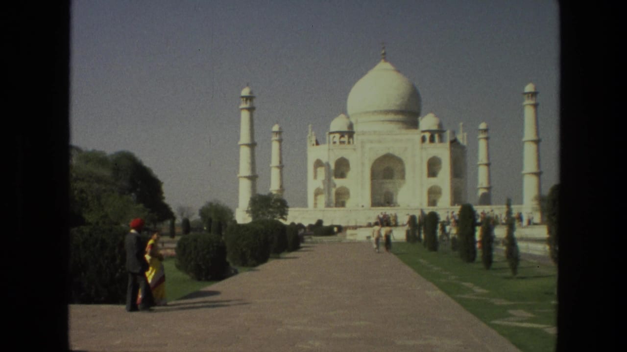 Wide 1974 India travel view with visitors on the approach path and the Taj Mahal centered beyond the gardens.