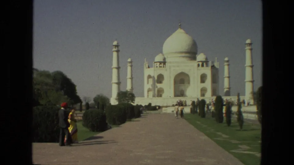 Wide 1974 India travel view with visitors on the approach path and the Taj Mahal centered beyond the gardens.