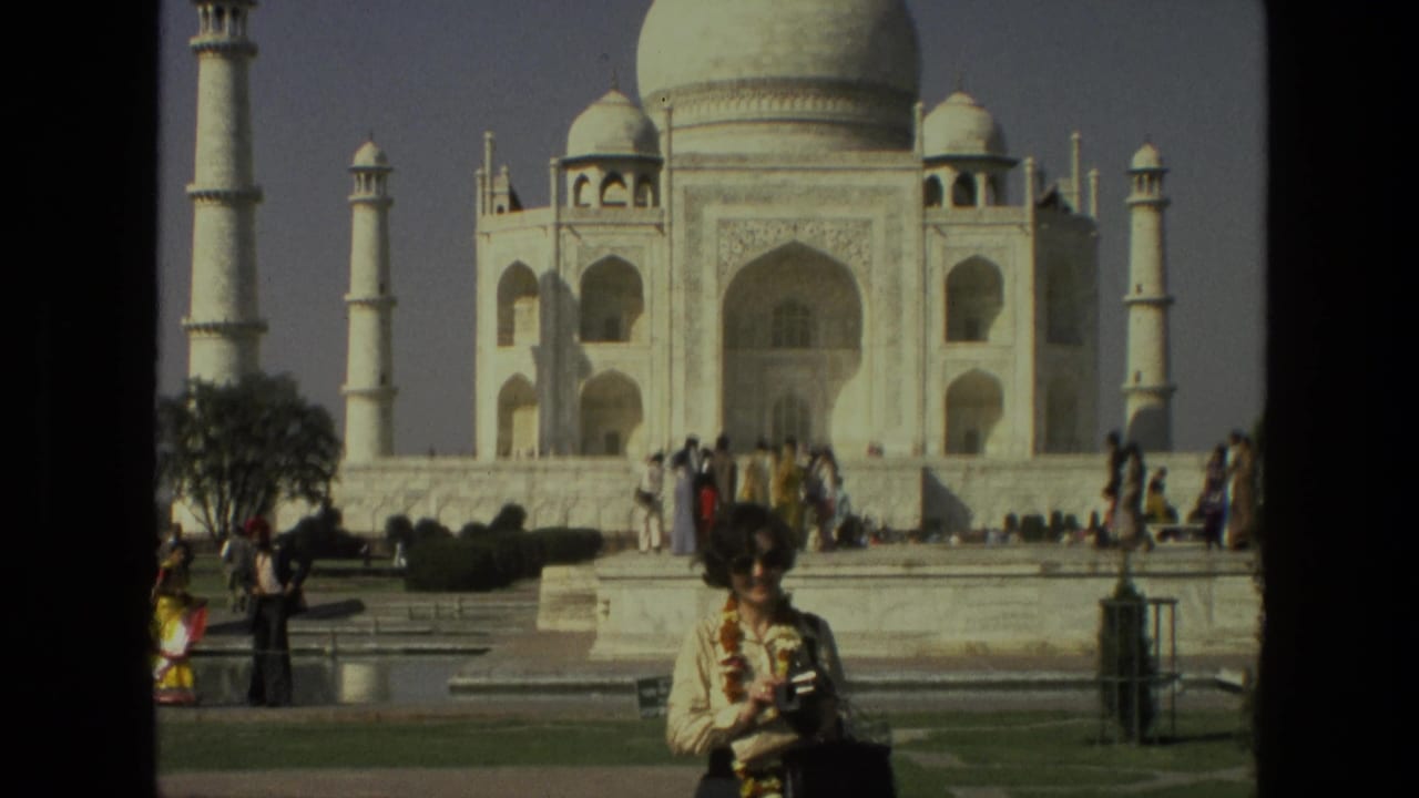Taj Mahal seen beyond tourists, with a woman in sunglasses standing in the foreground.