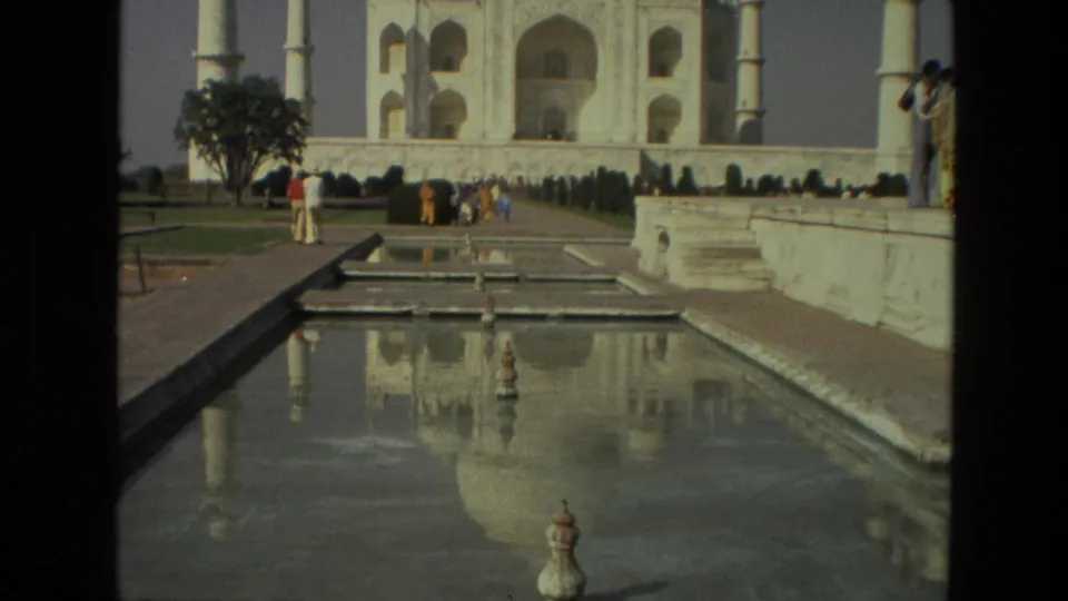 1974 home-movie view of the Taj Mahal grounds, with reflecting water, garden paths, and tourists along the terrace and walkway.