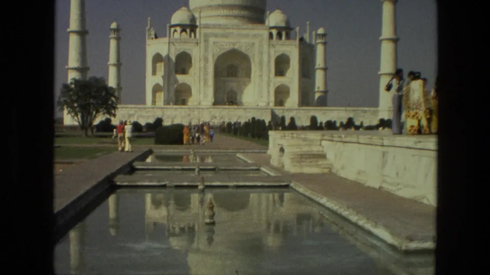 Visitor-shot 1974 view of the Taj Mahal from the garden axis, showing tourists near the pool and the mausoleum reflected in the water.