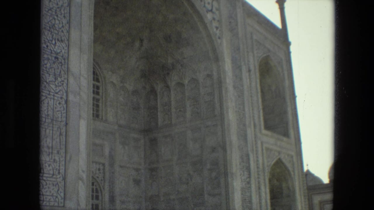 Close view of decorated arches and pale stone wall divided by a dark foreground strip.