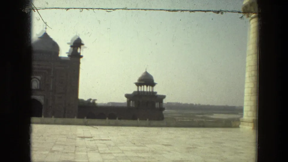 Visitor-shot 1974 8mm footage in India looks across a broad paved courtyard toward domed pavilions and tower-like forms under a hazy sky.