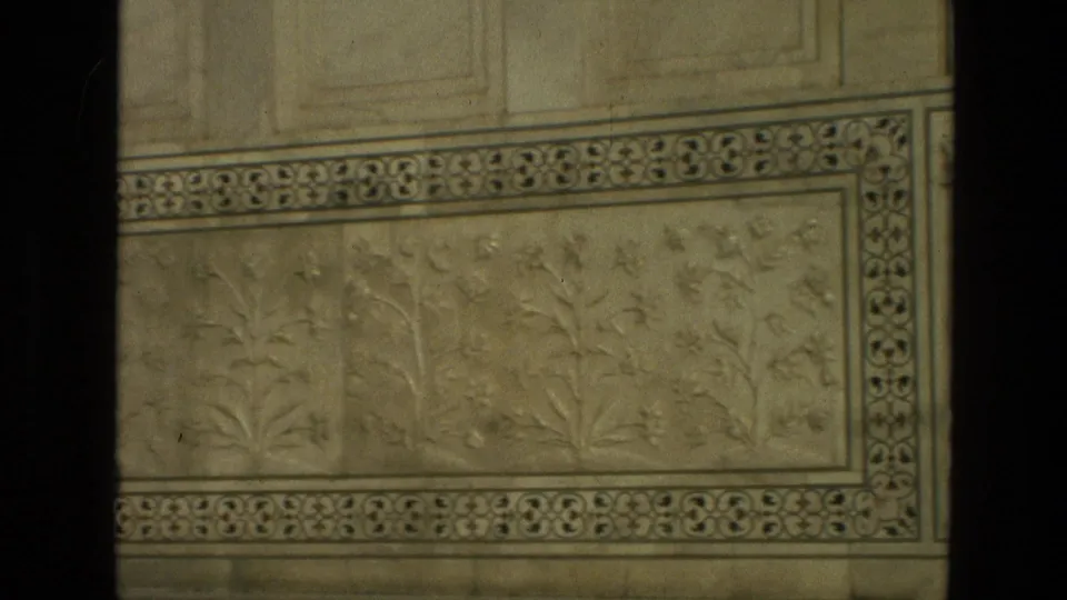 1974 India 8mm frame focused on a Taj Mahal marble wall panel with floral relief carving, ornamental border, and aged color fade.