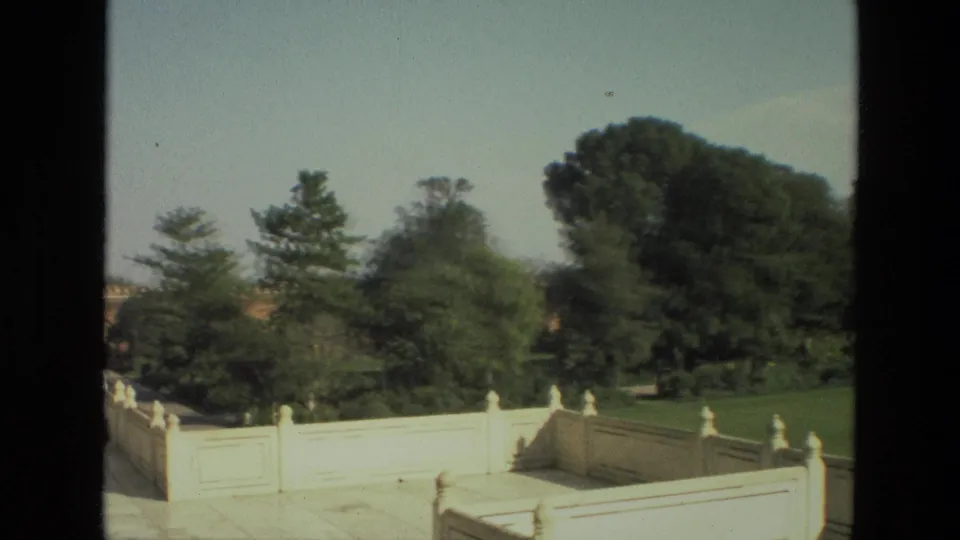 1974 8mm view of marble railings, lawns, and trees within the Taj Mahal grounds in India.