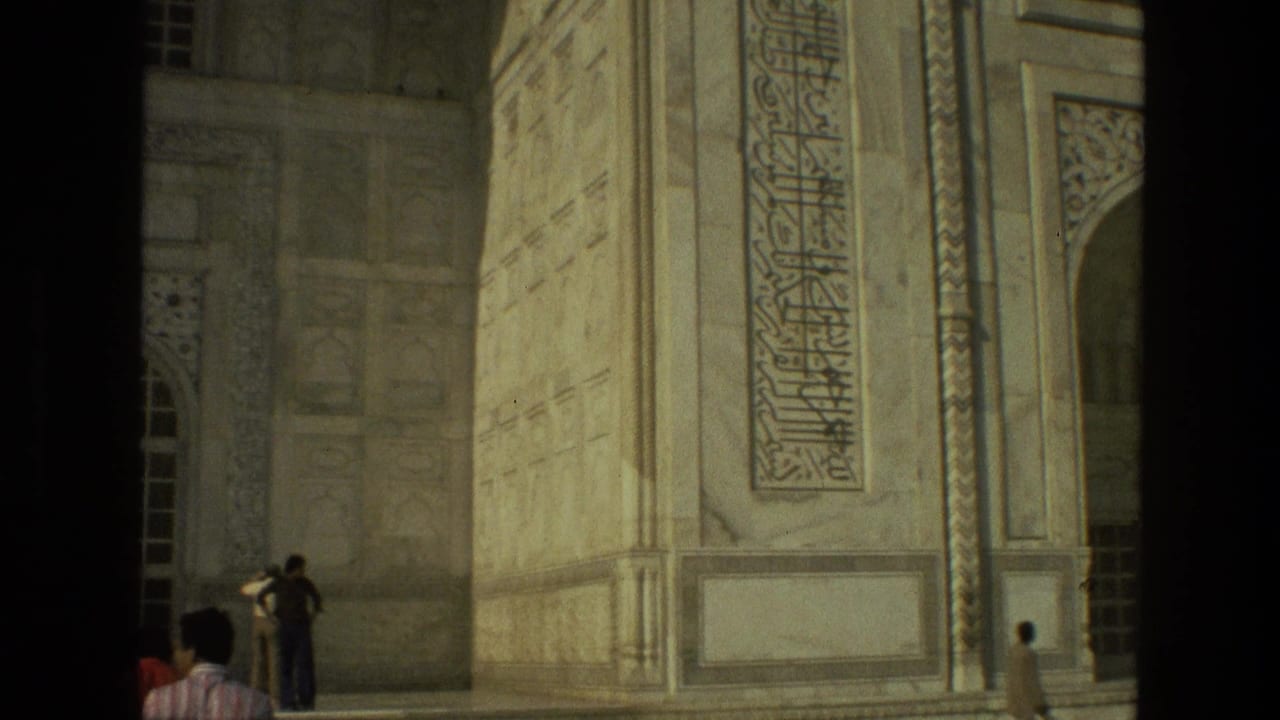 Tourists stand near a tall carved facade with arched openings and calligraphy panels.
